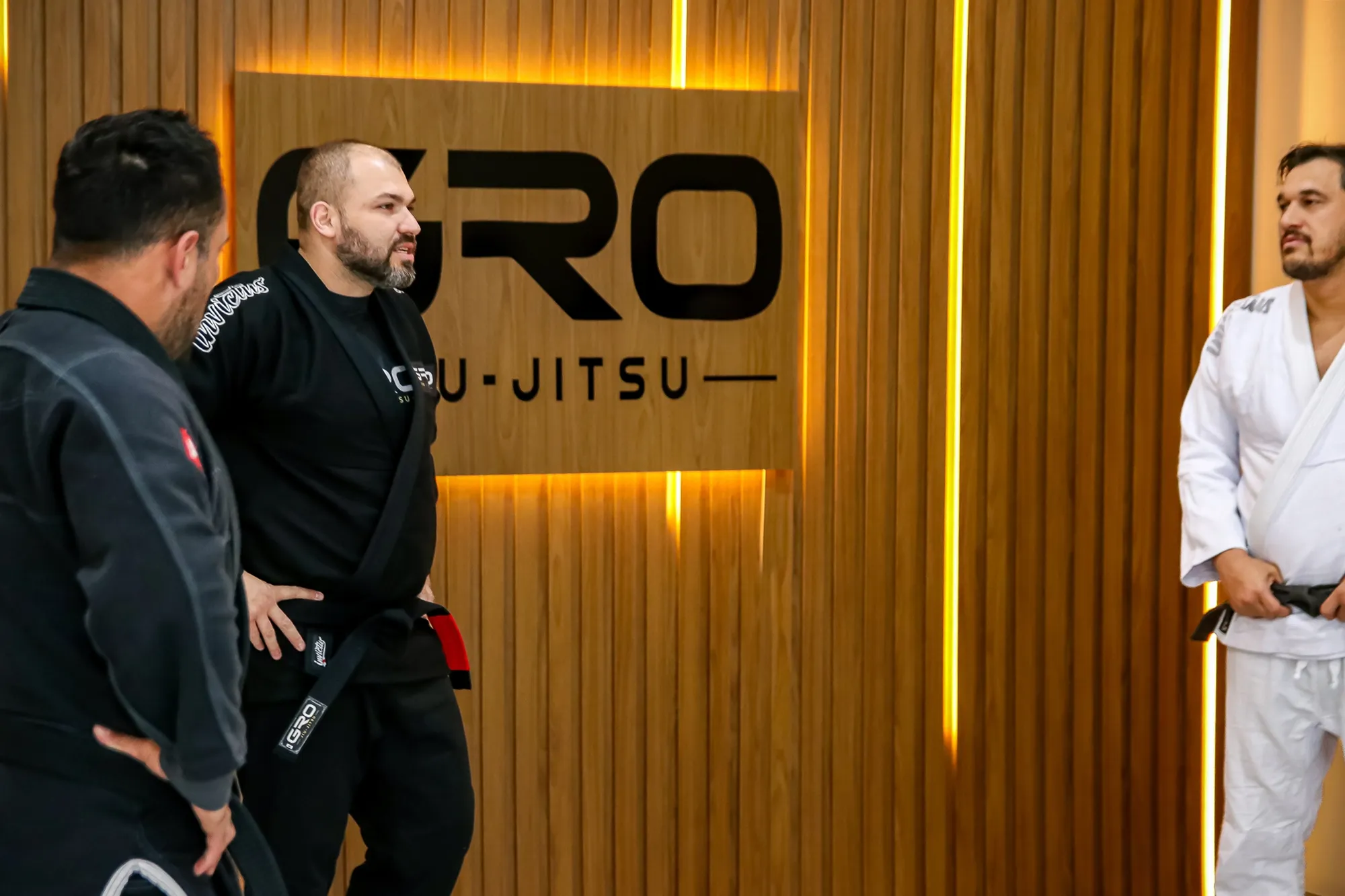 Professor Gustavo com alunos em frente ao painel da GRO Jiu-Jitsu